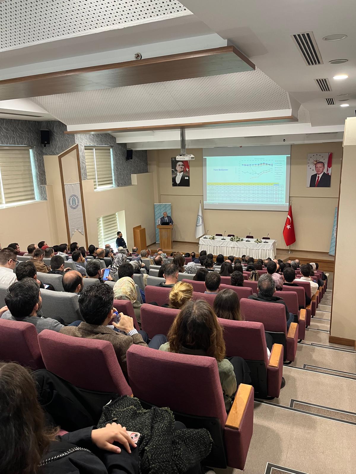 Dekanımız konuşmasını yaparken dinleyicileri de içine alan arkadan çekilmiş bir fotoğraf.