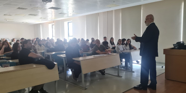 A speaker from Seranit Group presents while students listen.