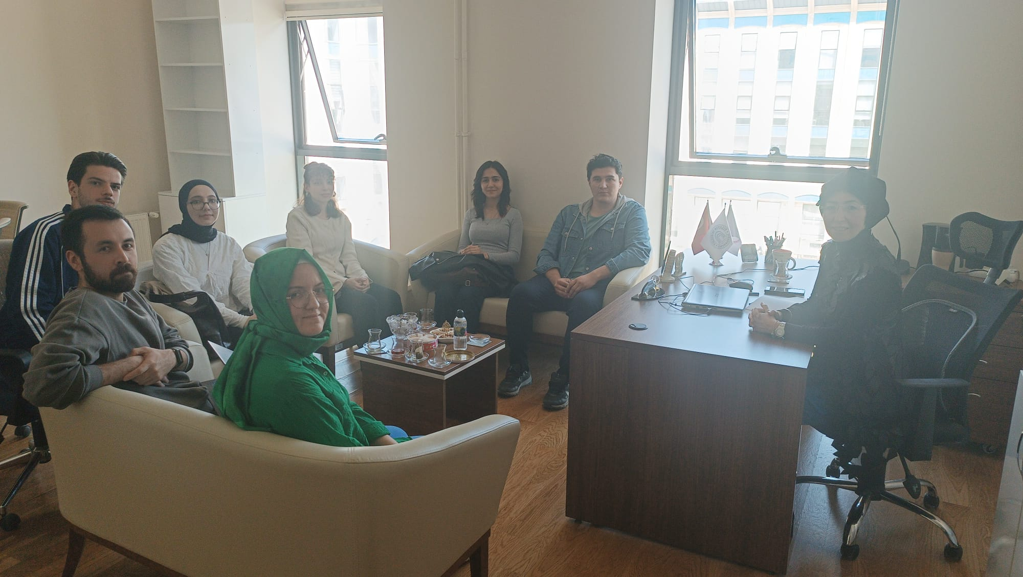 TR: AYBÜ Psikoloji Bölümü öğrenci temsilcileri bir ofiste toplantı gerçekleştiriyor. EN: AYBU Psychology Department student representatives are holding a meeting in an office.