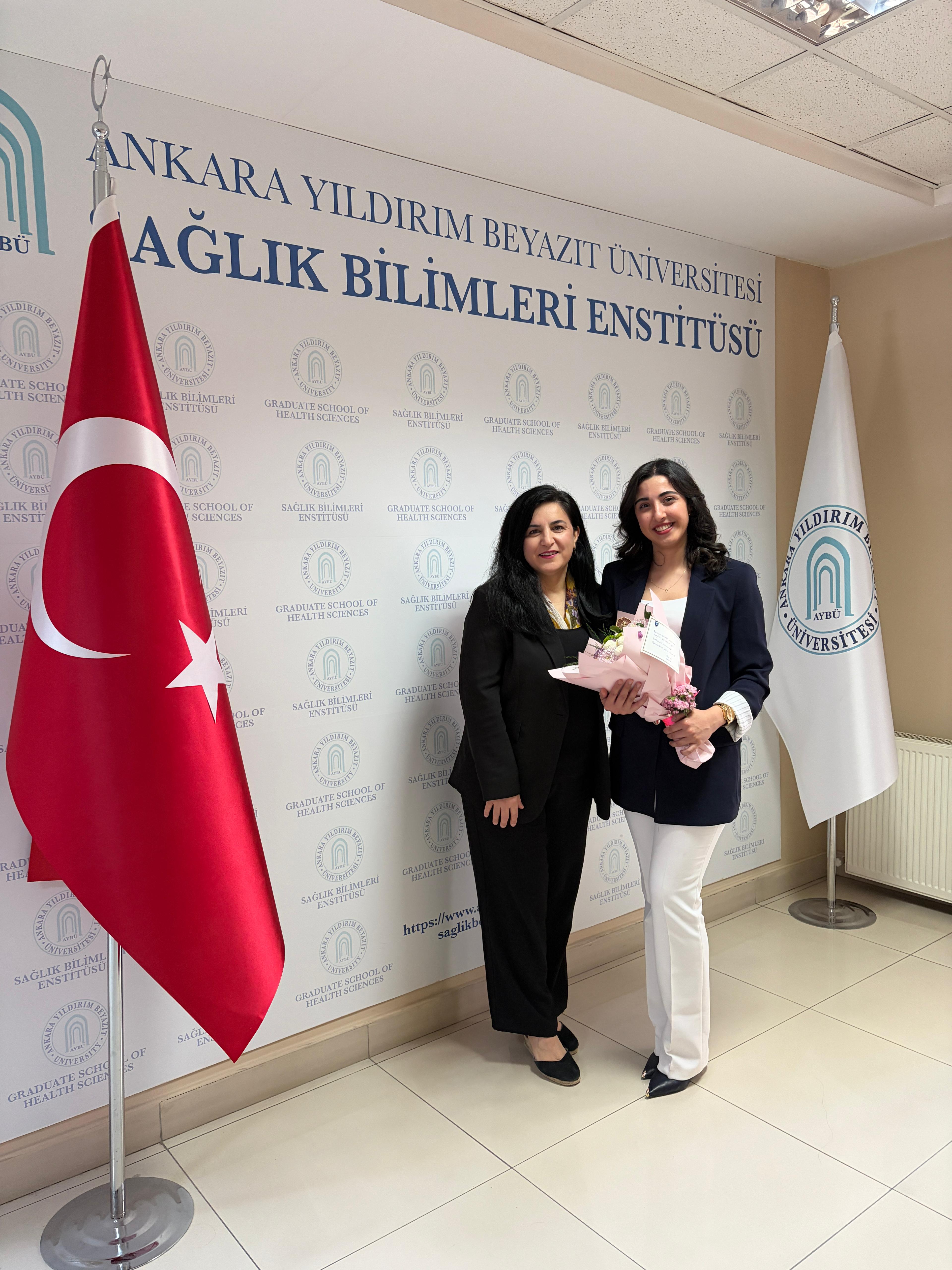 Görselde, tez savunmasını tamamlayan öğrenci ve danışmanı ile jüri üyelerinin birlikte yer aldığı bir fotoğraf bulunmaktadır.