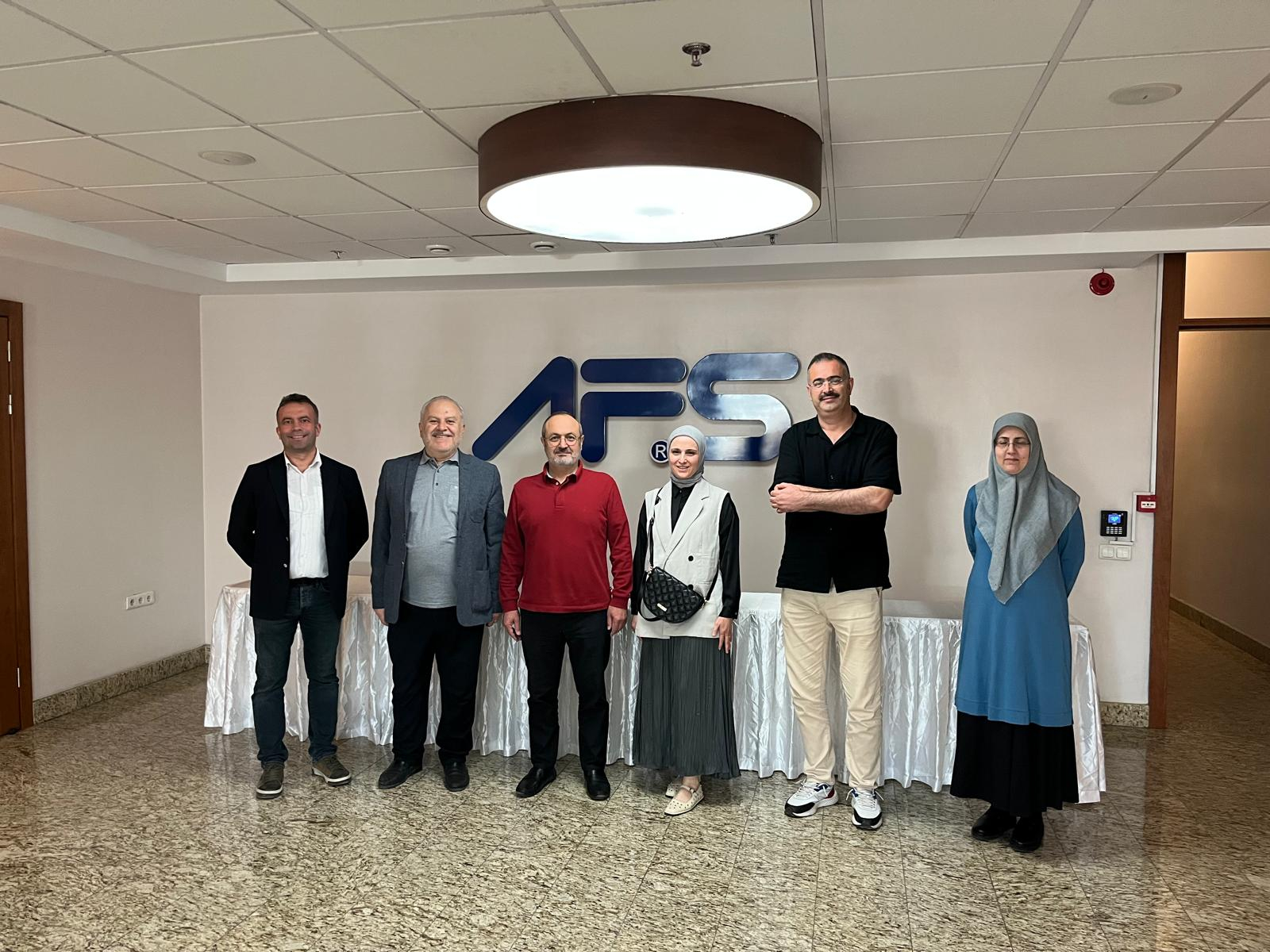 AFS FLEX binasında AFS logosu önünde toplu fotoğraf.
