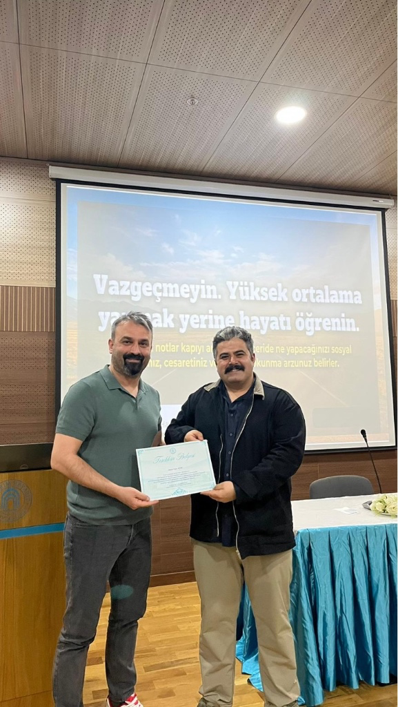 Oğuz Kuru'nun Dr. Öğr. Üyesi Erdinç Alaca'dan belgesini alırken çekilmiş bir fotoğrafı