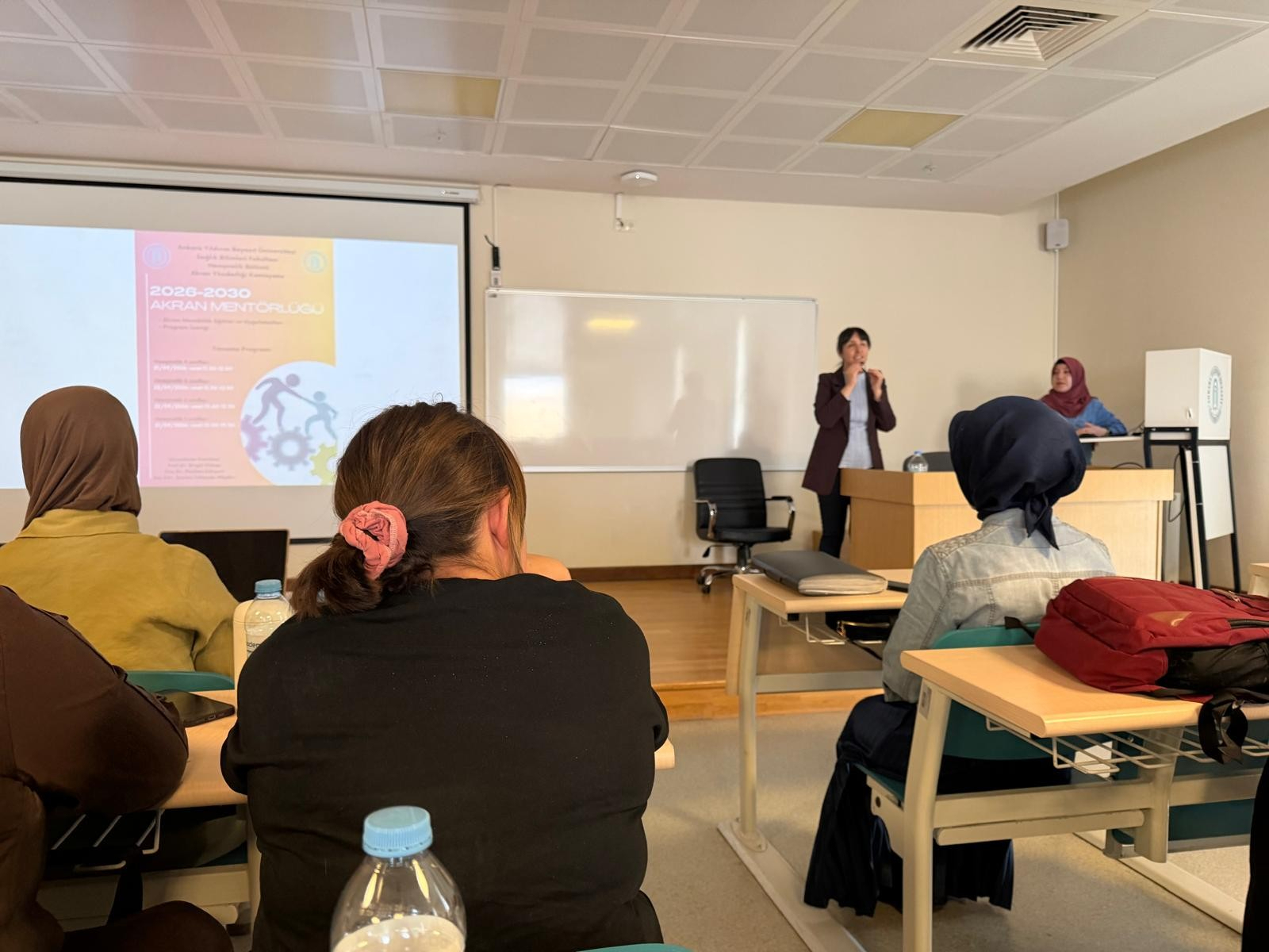 Associate Professor Reyhan Eskiyurt and Research Assistant Şeyma ALBAKIR introducing the Mentor–Mentee Program poster to third-year students.